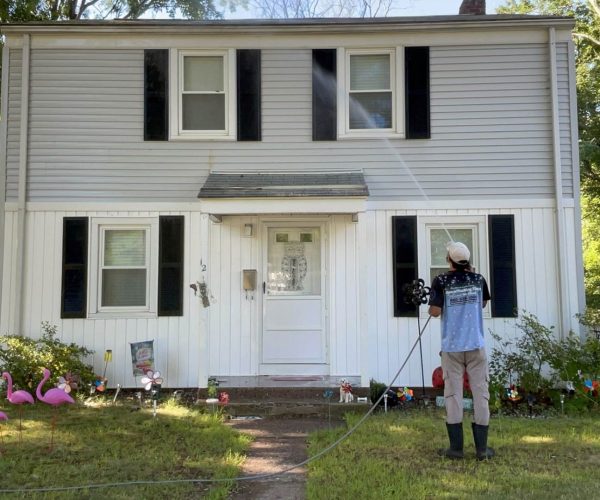 The PowerWashing Kings professiona washing siding of gray and white home